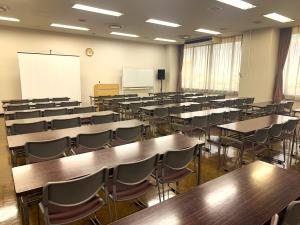 無人の第4会議室。長机と椅子、スクリーンがある学校形式の室内。