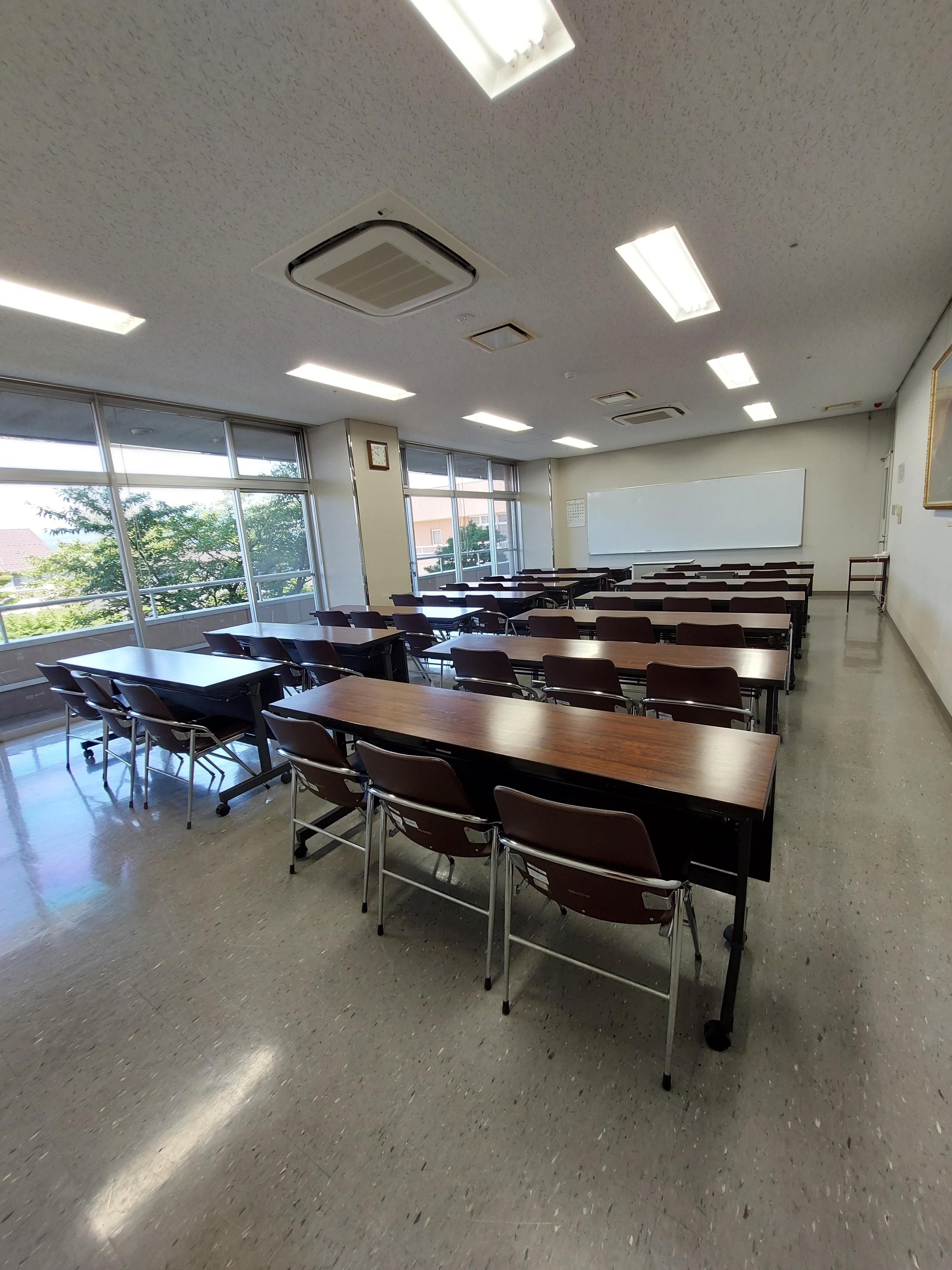 会議室（大）。窓とホワイトボード、机と椅子がある。