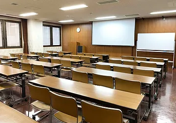 甚目寺産業会館の大研修室（第1）。前方にスクリーンを備え、机と椅子が並ぶ室内。