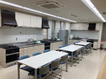 実習室。調理台とテーブル、椅子が配置されている。