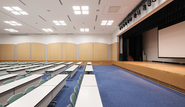 サンメッセ香川の大会議室。机と椅子、ステージを斜めから撮影した室内。
