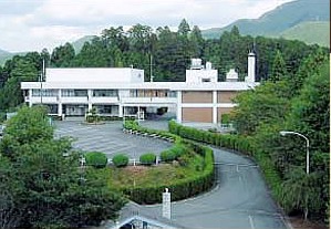 愛知県奥三河総合センターの外観。緑に囲まれた建物と車寄せの園路が見える公式写真。