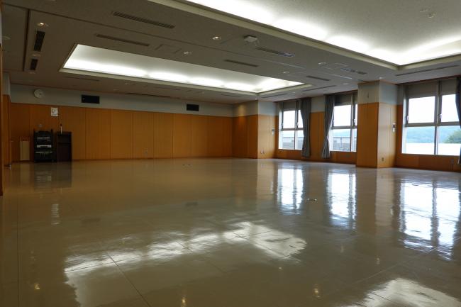 大会議室。広い床面と窓のある室内。