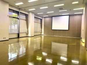 無人の大会議室1。スクリーンのある明るい室内。