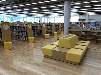 白岡市生涯学習センター（こもれびの森）の1階開架スペース。本棚と閲覧用ソファがある室内。