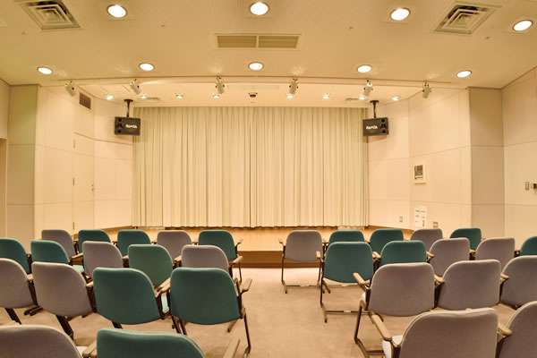 椅子席と前方の舞台が見える室内。