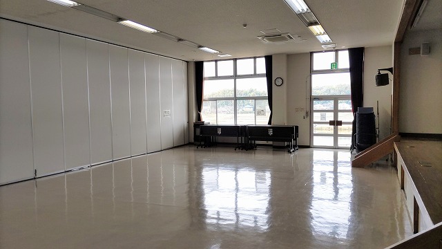 三日月橋生涯学習センター第1研修室。ステージのある広い室内に可動式間仕切りが見える。