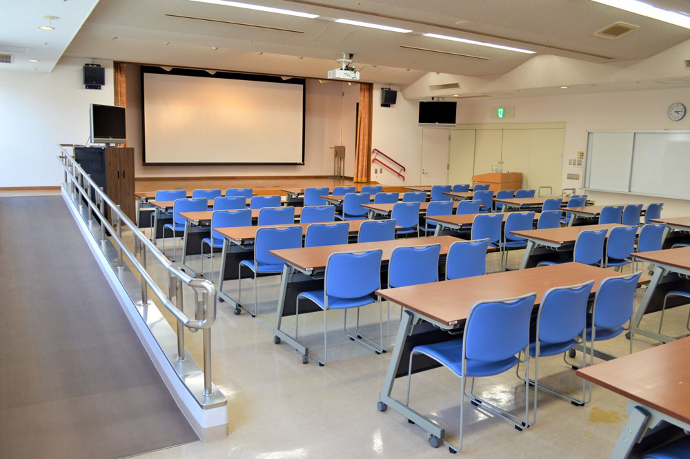 机と椅子、スクリーンを備えた第1研修室。