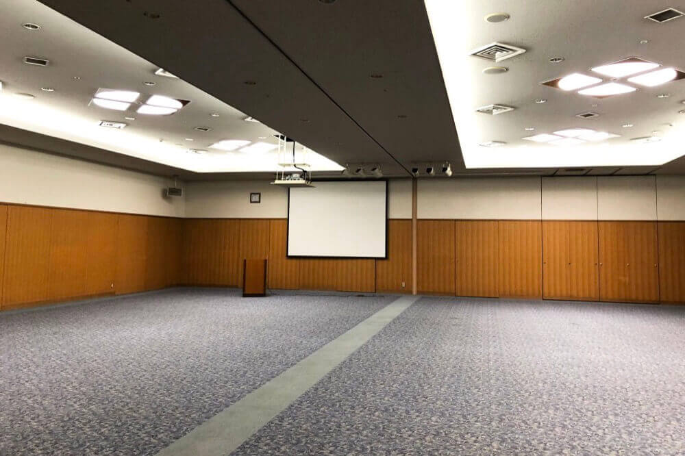 大集会室。広い室内に分割用の可動壁とスクリーンが見える。