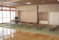 ふれあいルーム（デイルーム）。机と座卓を備えた室内。