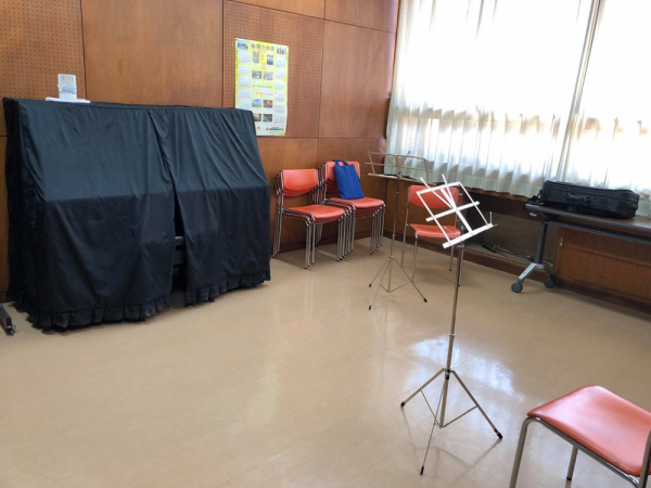 白岡市コミュニティセンターの音楽室。ピアノや譜面台が置かれた室内。