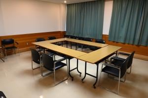 研修室。机と椅子、黒板を備えた無人の室内。