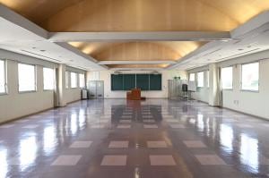 大会議室。窓と黒板、演台を備えた無人の室内。