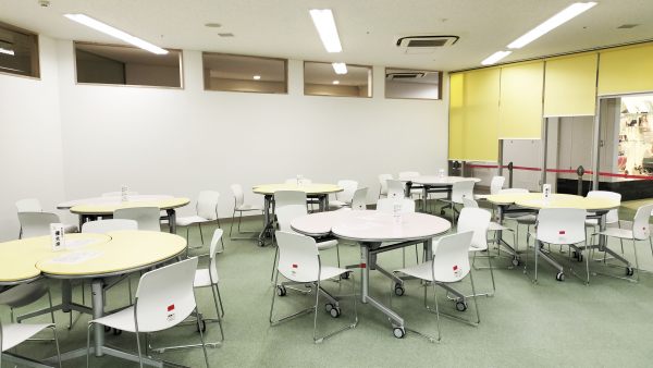 越谷市市民活動支援センターの多文化交流ひろば。丸テーブルと椅子が並ぶ交流スペース。
