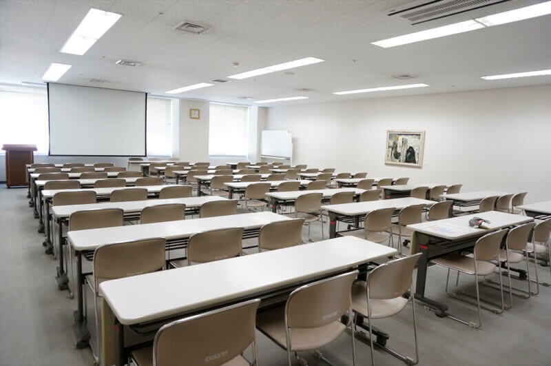 講習室401。スクール形式の机と椅子、スクリーンが見える。