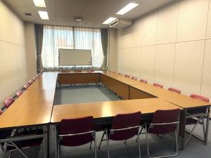 無人の第2会議室。ロの字型に机と椅子が配置された室内。