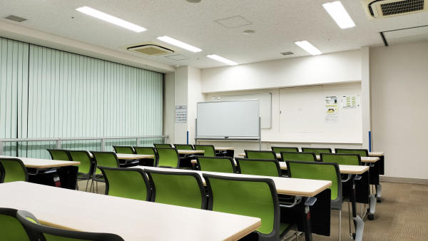 越谷市市民活動支援センターの活動室A。机と椅子、スクリーンが配置された室内。