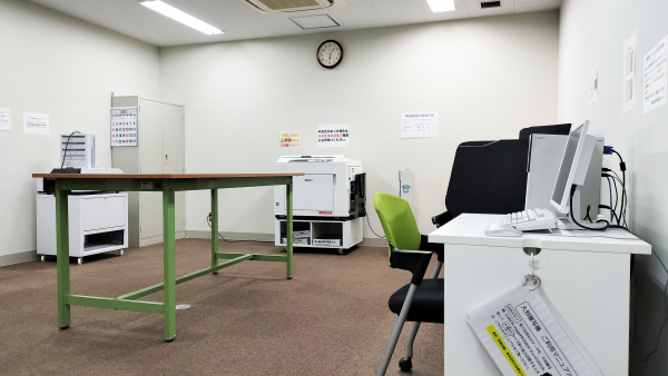 越谷市市民活動支援センターの印刷作業室。印刷機器と作業机が配置されている。
