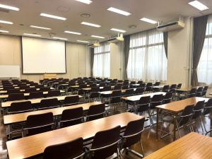 無人の大会議室2。机と椅子が並ぶ学校形式の室内。